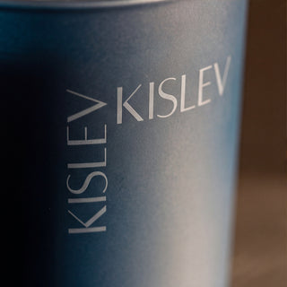 Close-up of an ocean blue cylindrical candle with the brand name 'KISLEV' printed vertically and horizontally in light gray text.